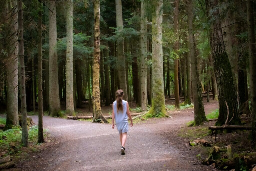 girl walking near trees, comes to a fork in the road, wondering where to go next with her hashimoto's journey