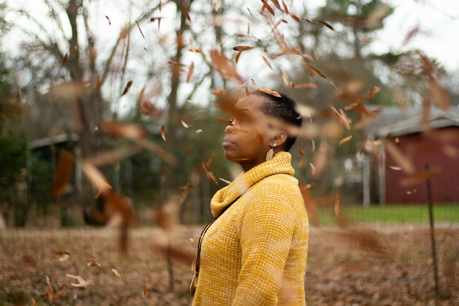 Photo by Paris Lopez woman in yellow knit sweater standing near brown trees during daytime