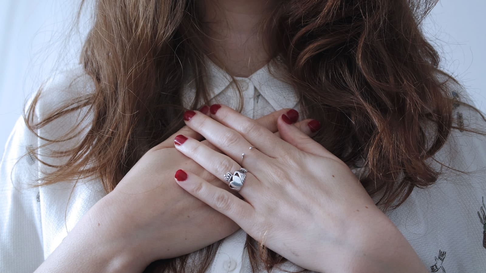 woman wearing silver-colored ring HER HANDS are on her heart