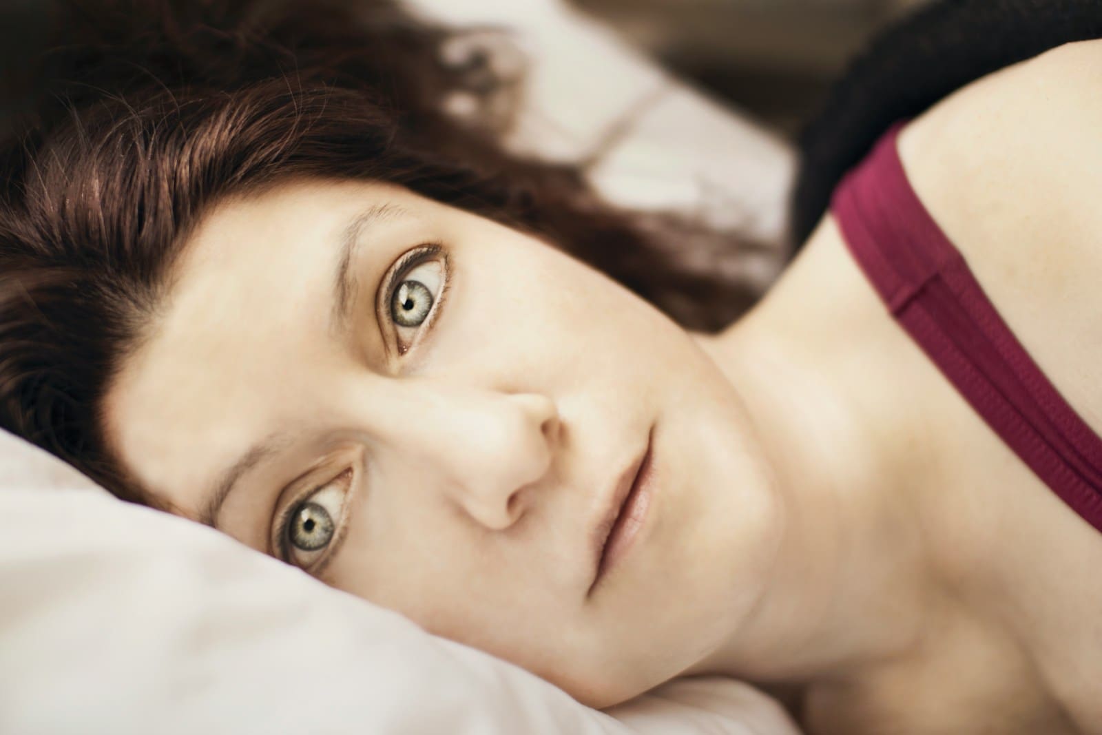 Photo by Jen Theodore a close up of a person laying on a bed. her blue eyes are open and she has brown hair