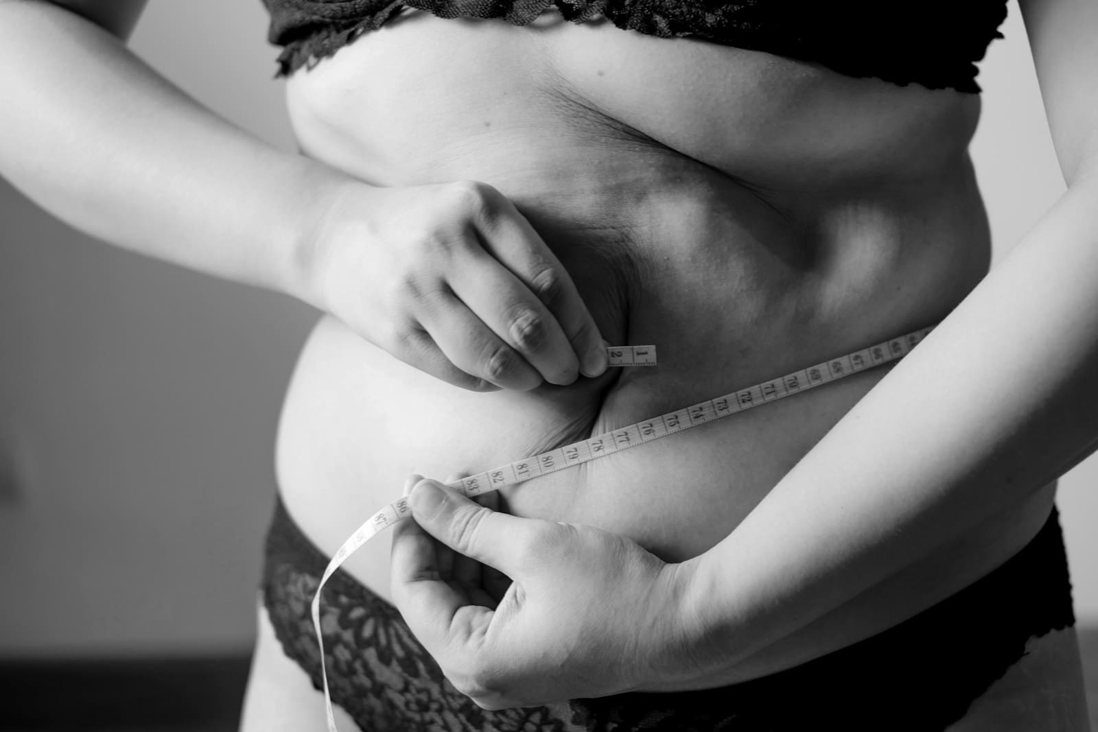 grayscale photo of woman holding her belly