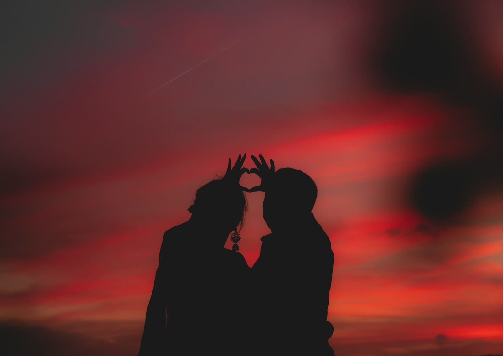 Photo by Dev Asangbam silhouette photography of two people making a heart shape with their hands. love and dating can be amazing at every age