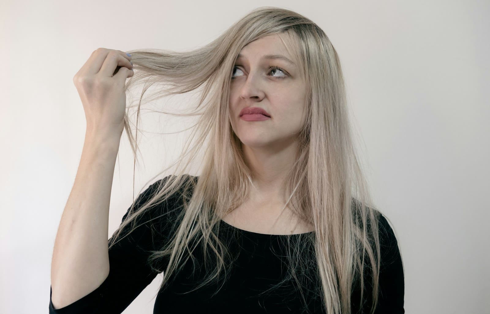 Photo by Sherise Van Dyk woman in black scoop neck shirt pulls her hair out critically as it is thin and brittle