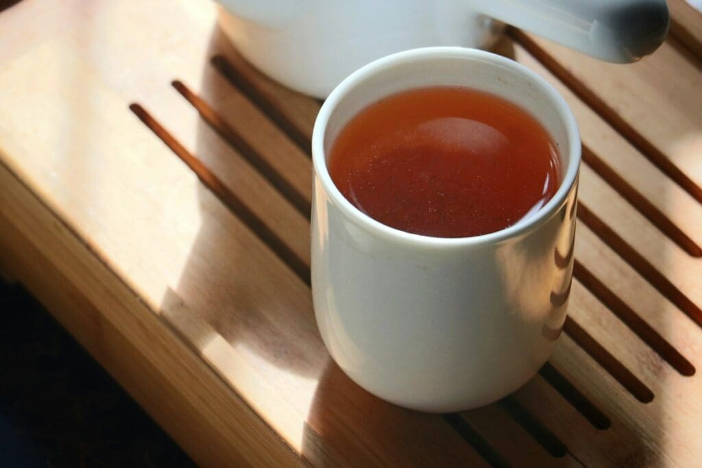 white cup on table filled with red korean ginseng tea