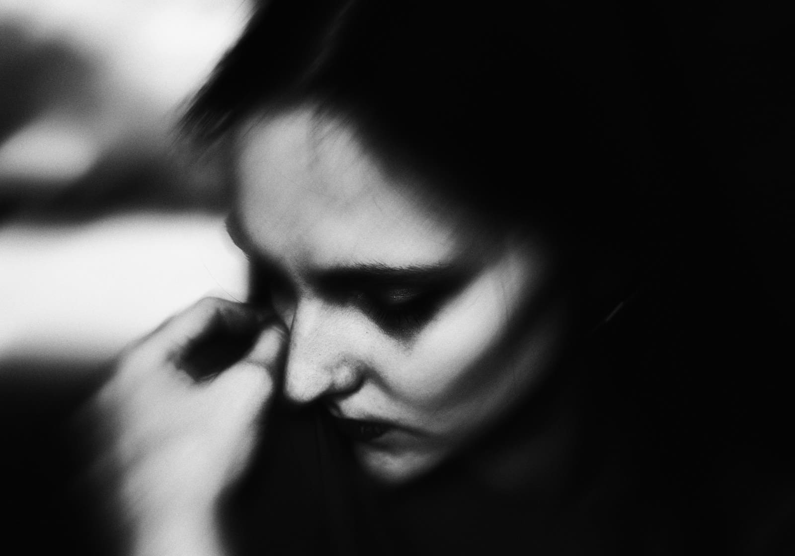 Photo by Vitaliy Shevchenko a black and white photo of a woman with her head bowed in grief.