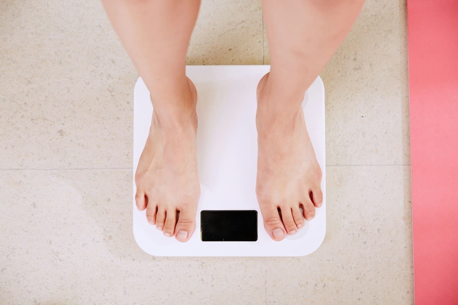 Photo by i yunmai person standing on white digital bathroom scale, the view is from the calf of the leg down