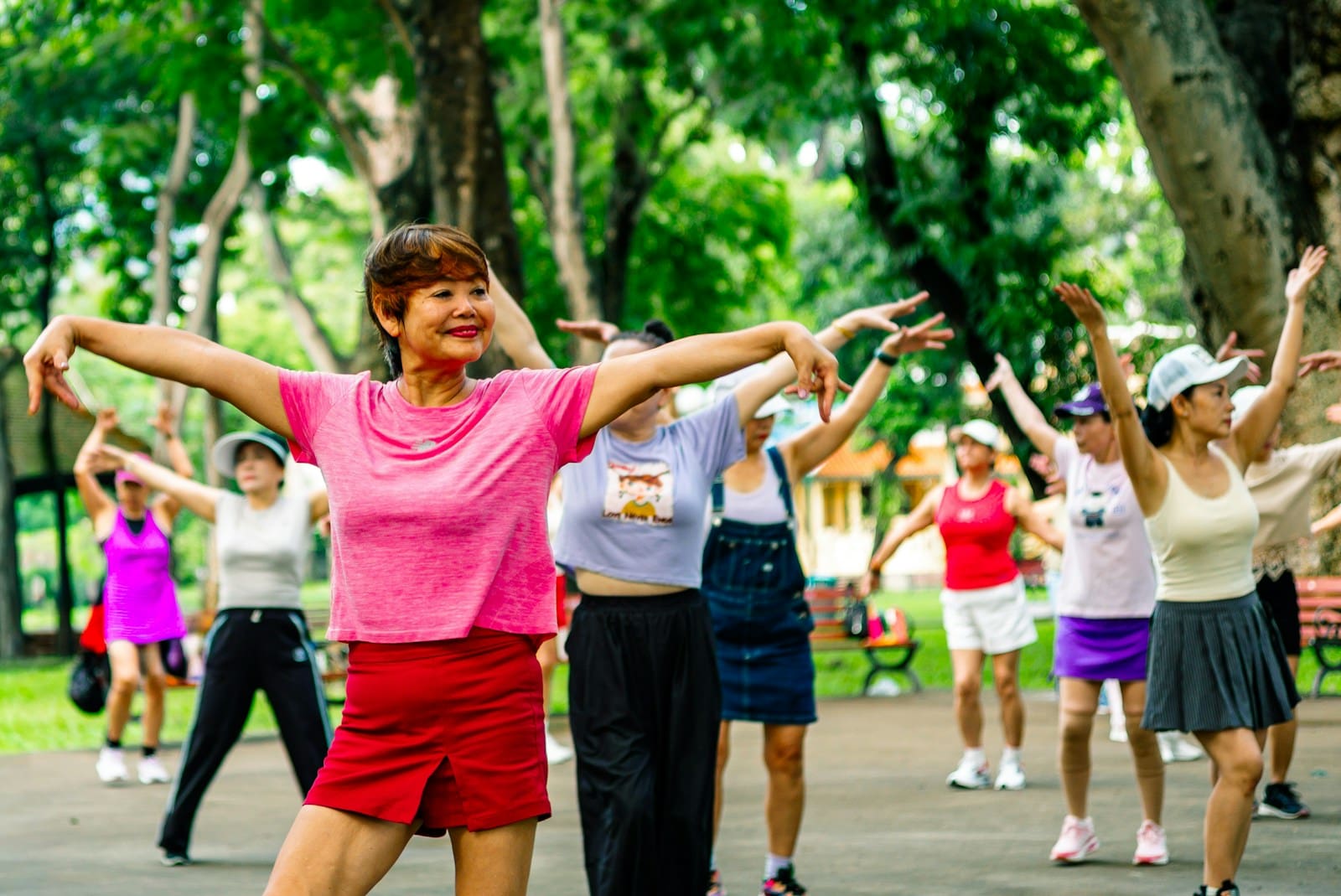 Photo by Khanh Do Group of women exercising together in a park. They are menopausal aged and vibrant in colorful clothes.