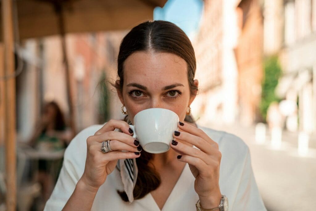 a woman holding a coffee cup and drinking. Coffee may well have health benefits