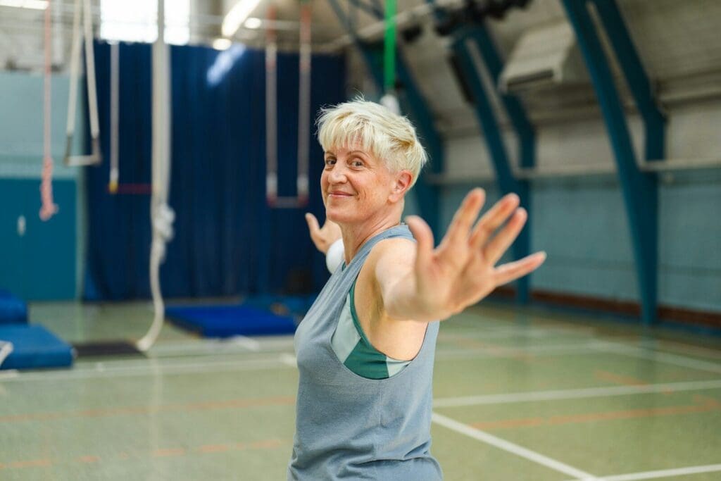 An older woman with short blonde hair in a gym exercising.