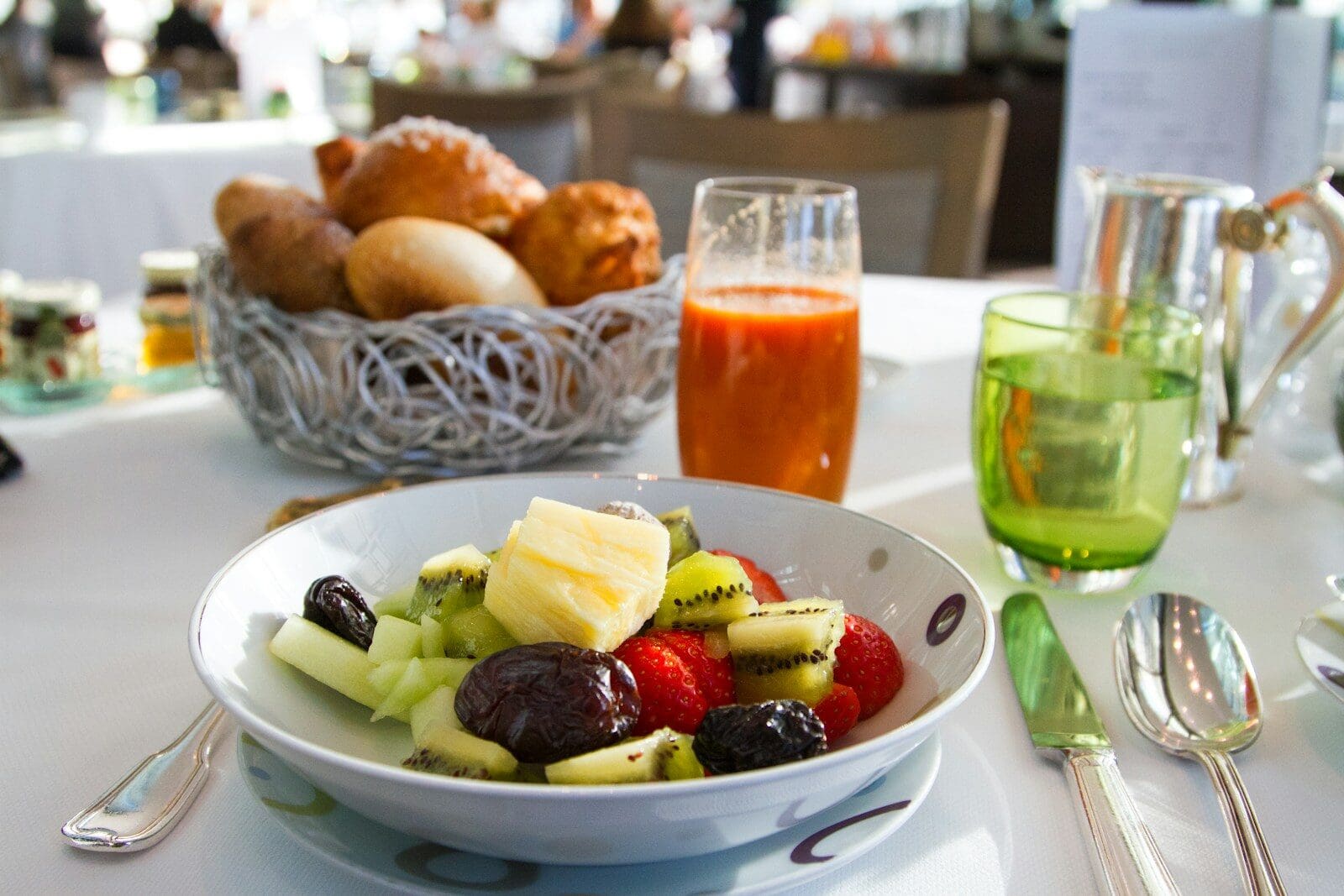 Photo by Kamala Bright a bowl of fruit including healthy prunes sitting on a table with cutlery and juice