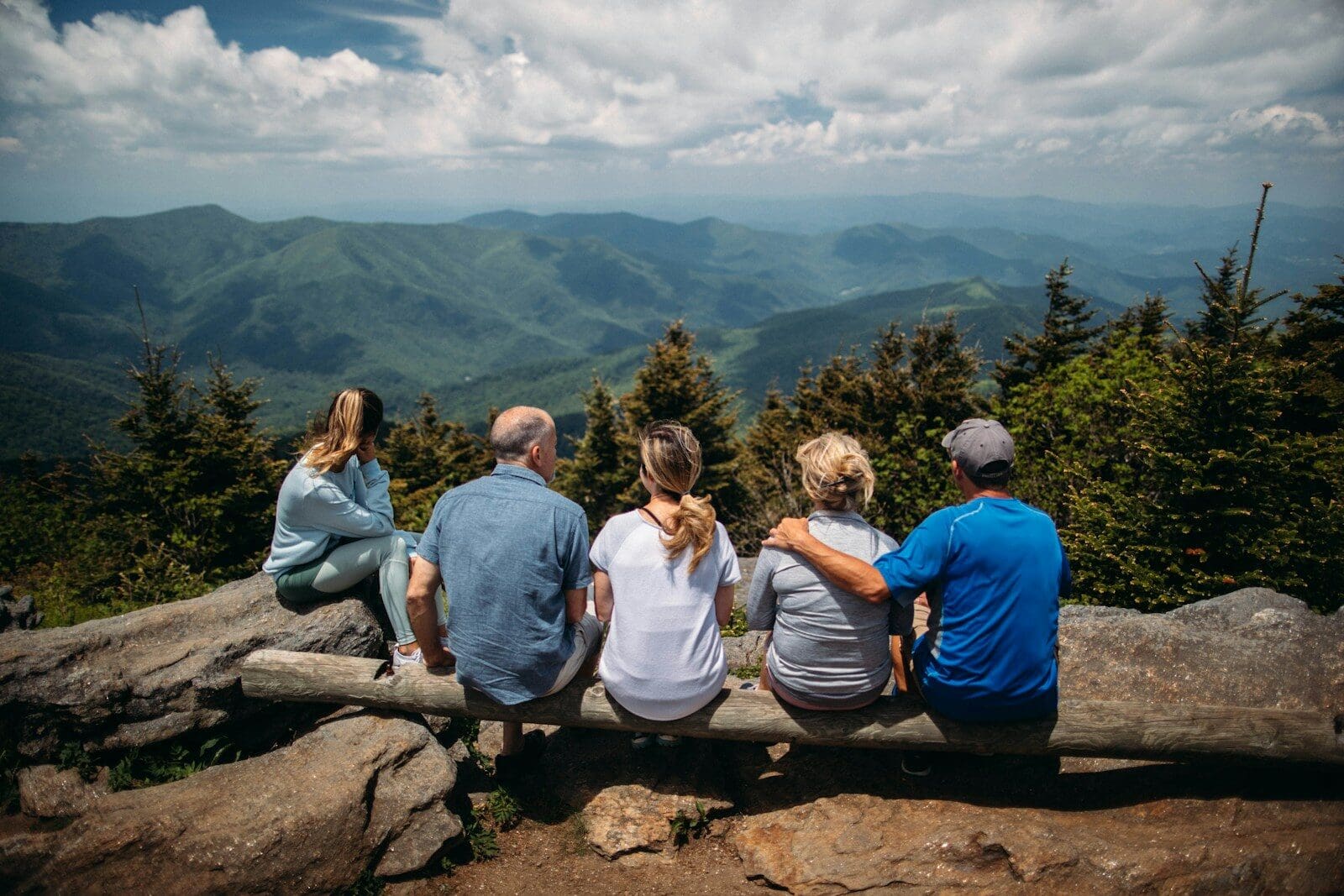 Photo by Roberto Nickson Multigenerational family sitting on rocks overlooking mountain. The sandwich generation can be filled with joy