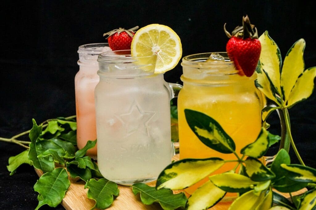 three mason jars filled with water, juice and herbal teas
