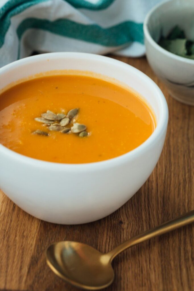 butter nut squash soup in white ceramic bowl topped with pepitas. Fall foods are so healthy and comforting.